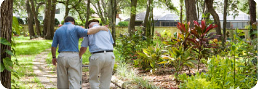 A male caregiver helping a senior man take a walk.