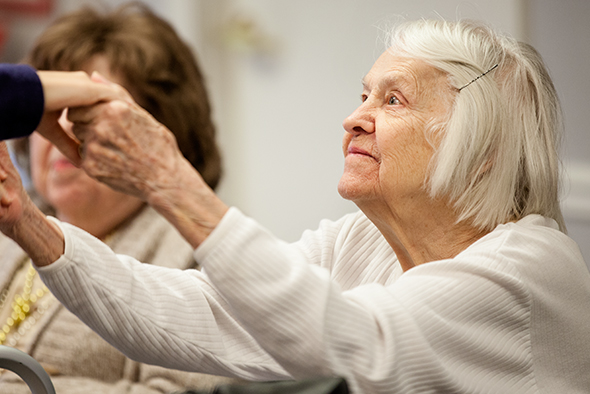 A caregiver holding the hands of a senior woman.