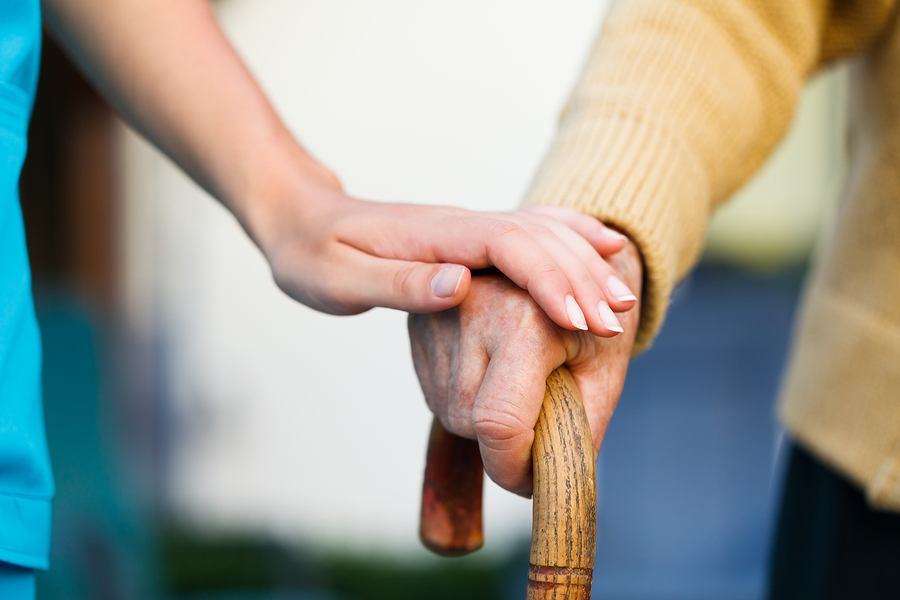 A caregiver holding a senior's hand.