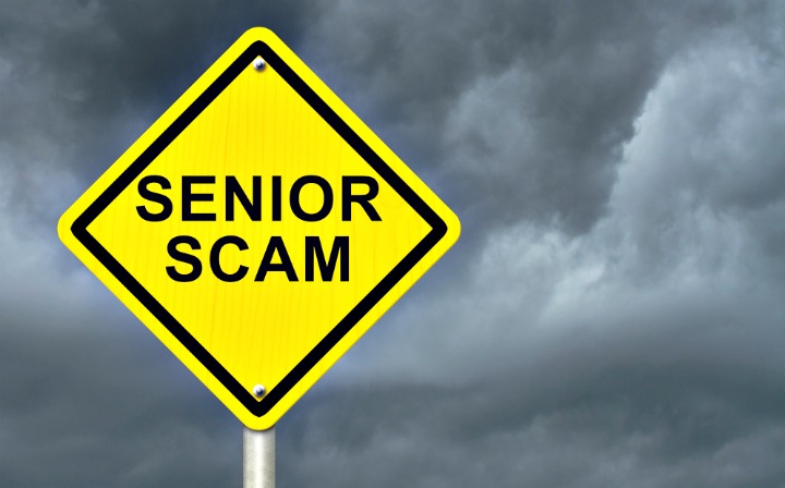 A sign that reads Senior Scam in front of dark clouds.