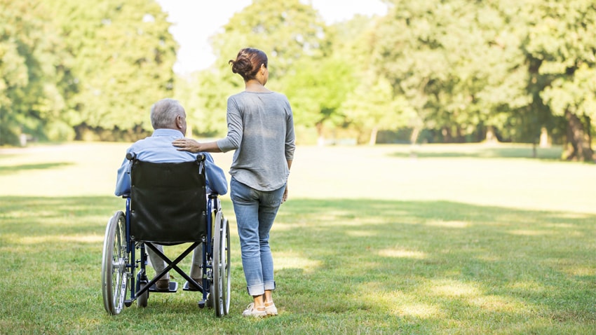 Caregiver supporting senior outside.