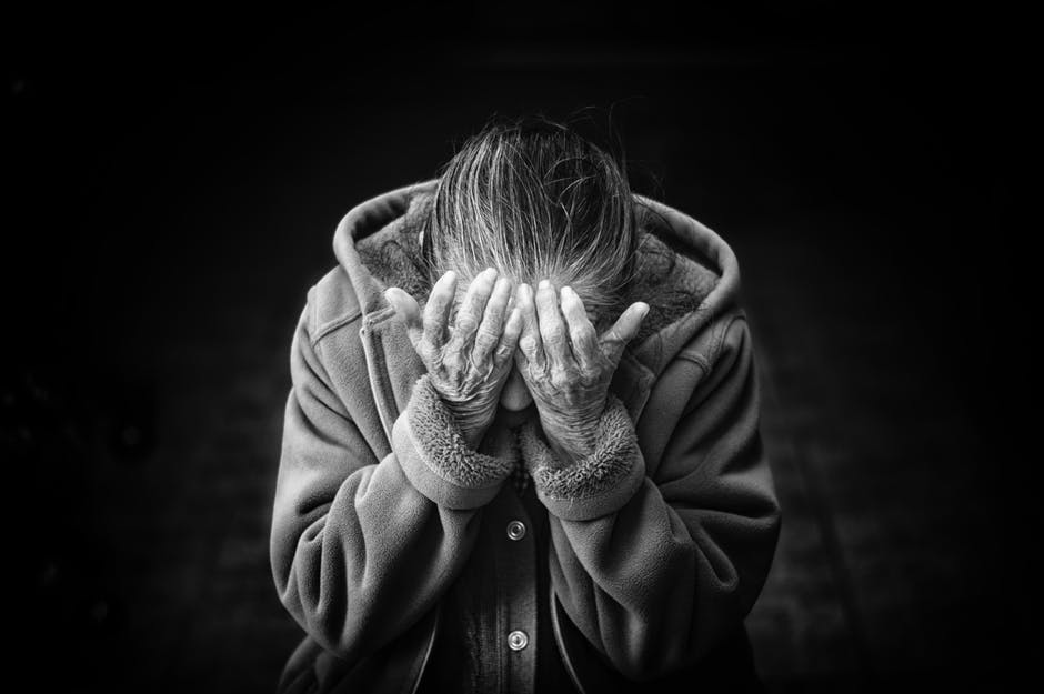 A senior woman sat with her head in her hands.