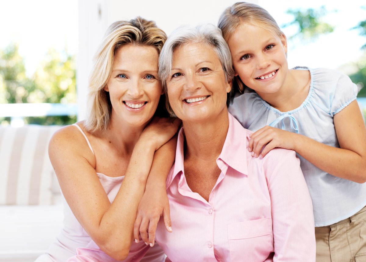 A grandmother, mother and daughter smiling together.