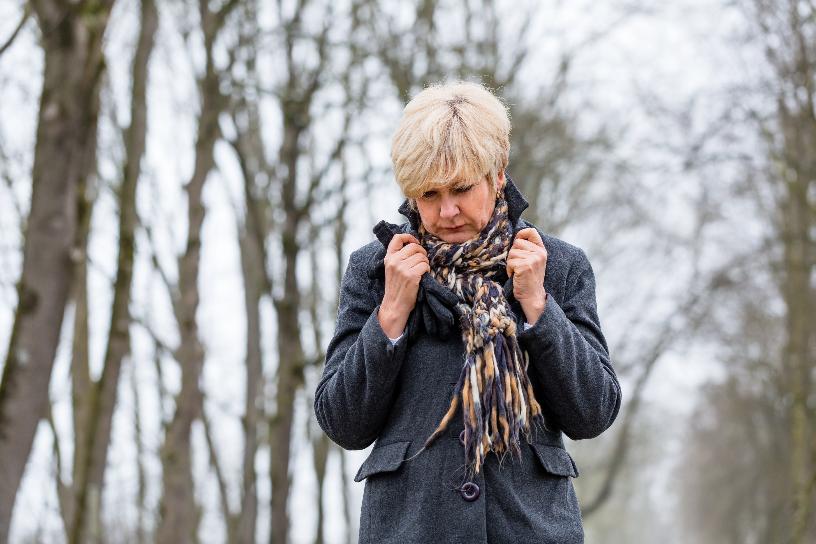 A senior woman looking unhappy while taking a walk on a cold day.