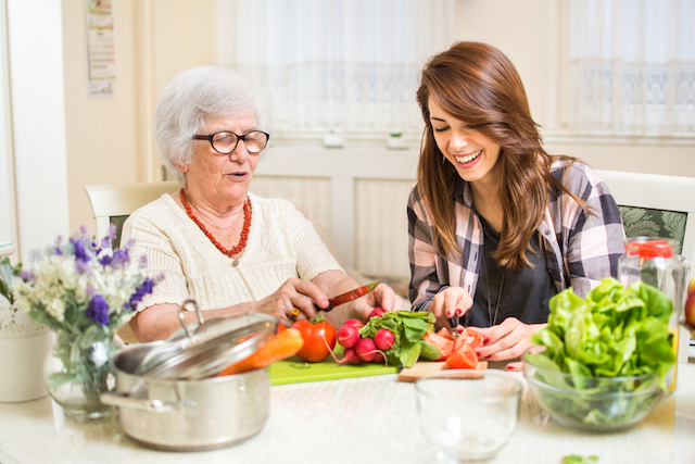 A senior woman preparing food with a young woman.