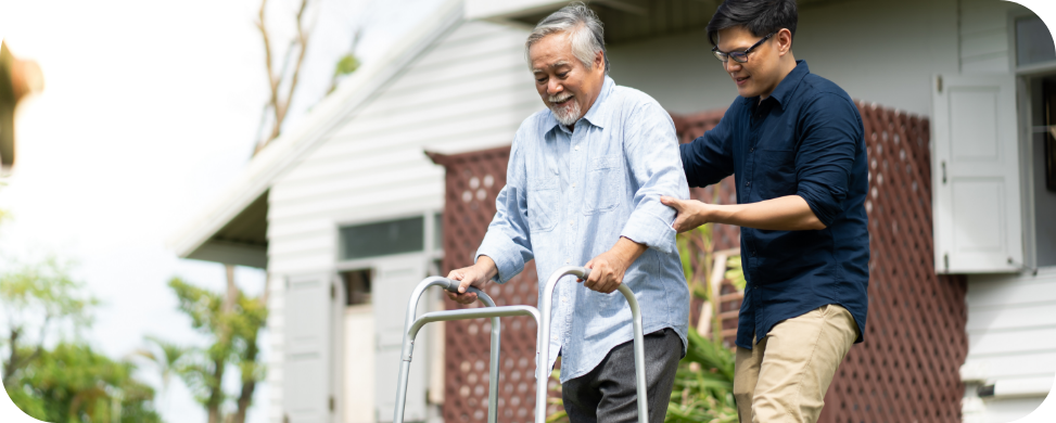 A caregiver helping a man using a walking frame.