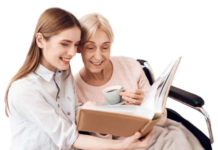 An eldery woman drinking tea and looking at a photo album with a young carer.