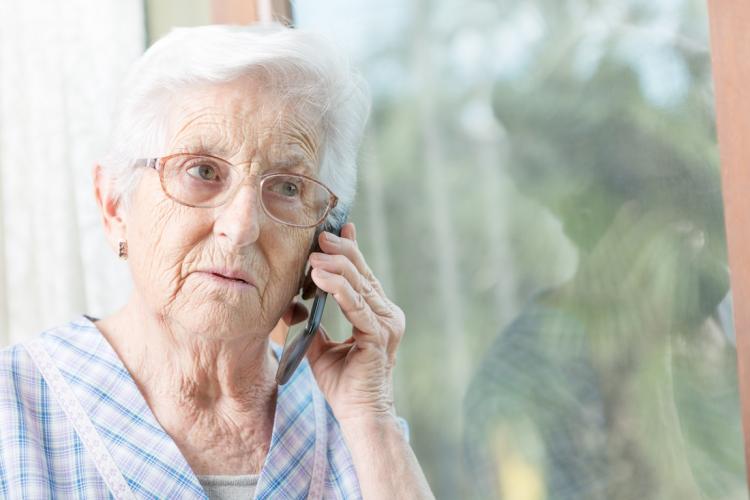 A senior woman looking worried while talking on the phone.