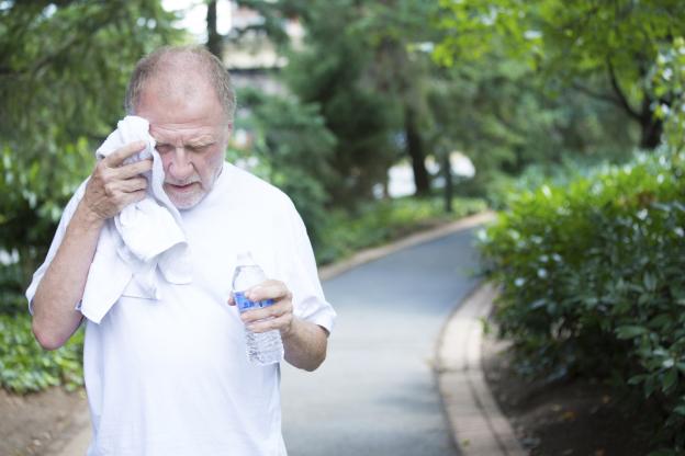 A senior man mopping his brow on a hot day.