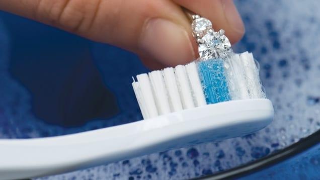 A photograph showing cleaning a diamond with a toothbrush.