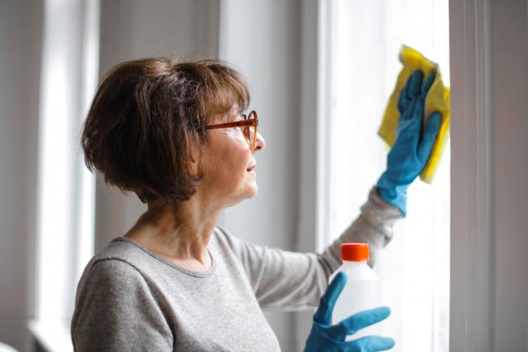 A senior woman cleaning a window.