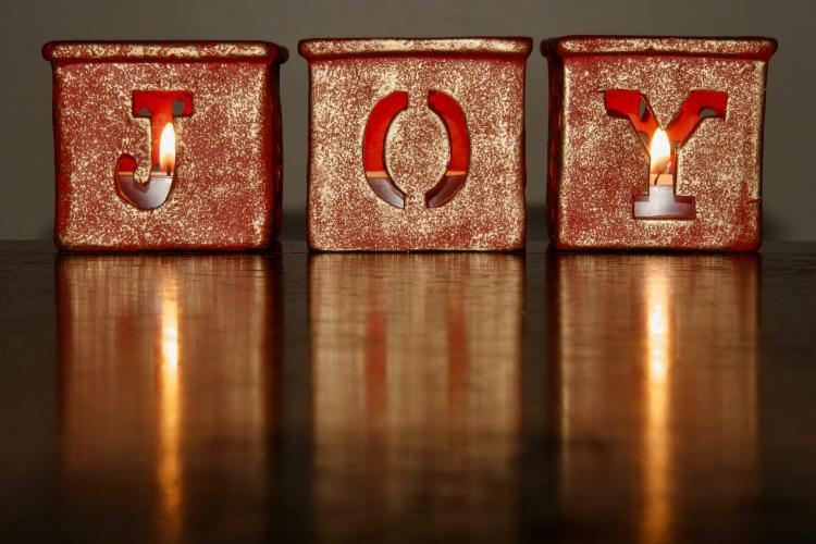 3 candles in boxes spelling out the word JOY.
