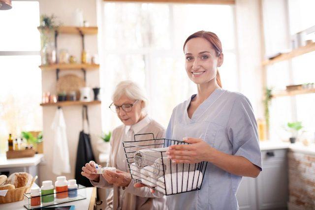 A photograph of a female caregiver helping a senior woman at home.